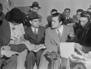 Photo of Orson Welles meeting with reporters in an effort to explain that no one connected with the War of the Worlds radio broadcast had any idea the show would cause panic. Future first Voice of America (VOA) director John Houseman was the producer of the War of the Worlds fake entertainment newscast.